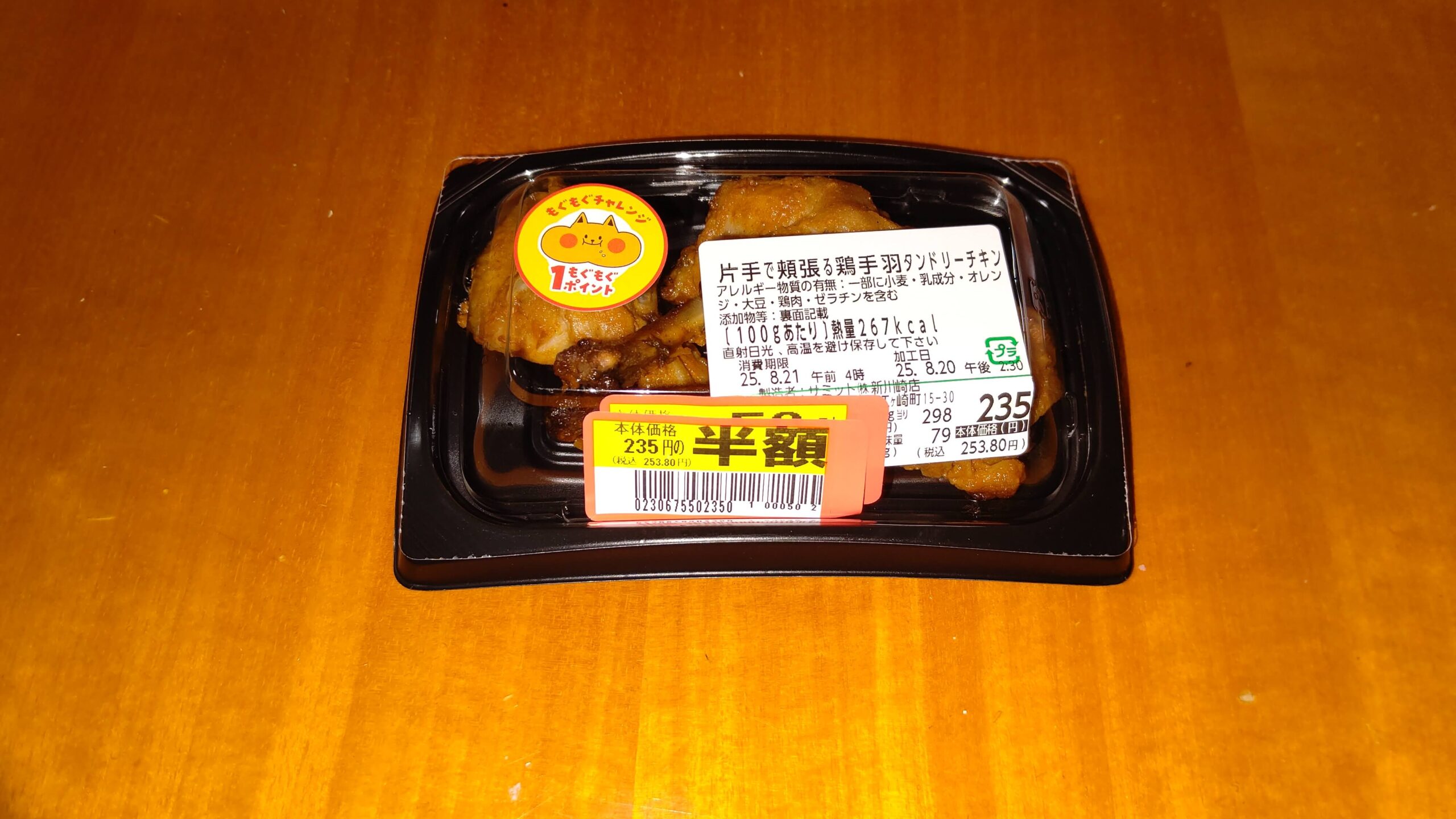 サミット新川崎店の片手で頬張る鶏手羽タンドリーチキン1パック235円の半額シールが貼られている画像